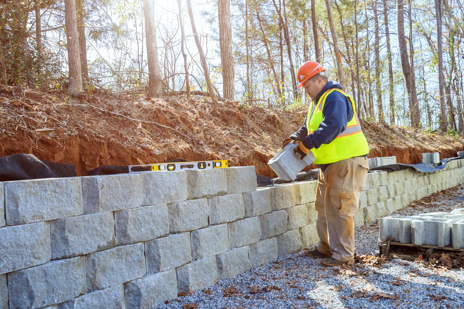 When developing new property construction worker uses cement blocks to build a retaining wall.